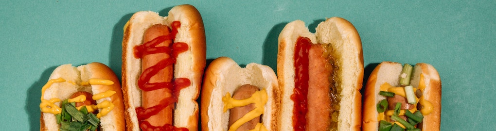 row of hot dogs with various sauces and condiments